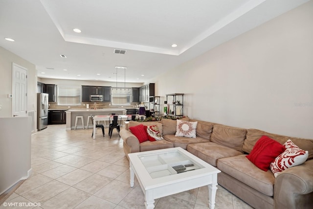 living room with a raised ceiling and light tile patterned flooring