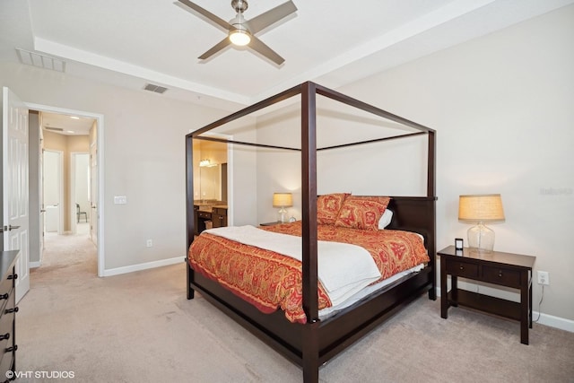 bedroom with ceiling fan, light carpet, and ensuite bath