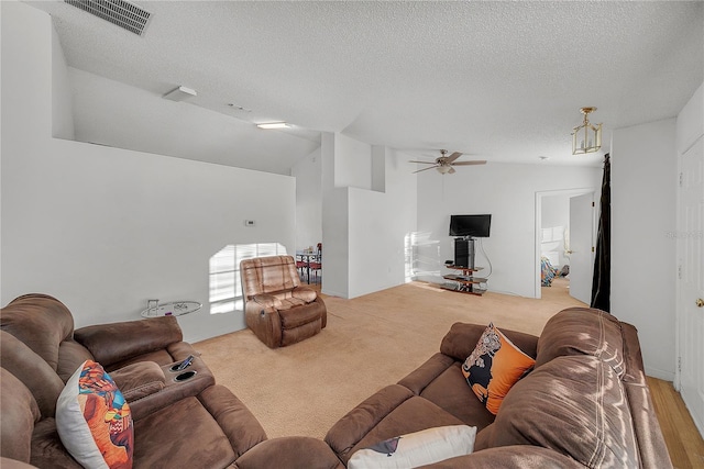 living room with a textured ceiling, ceiling fan, and lofted ceiling