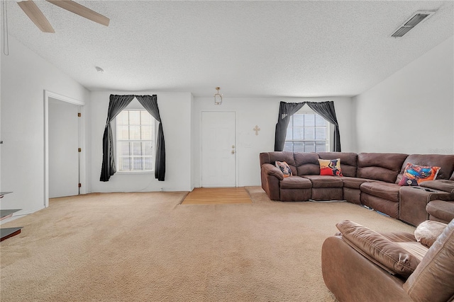 carpeted living room featuring ceiling fan and a textured ceiling