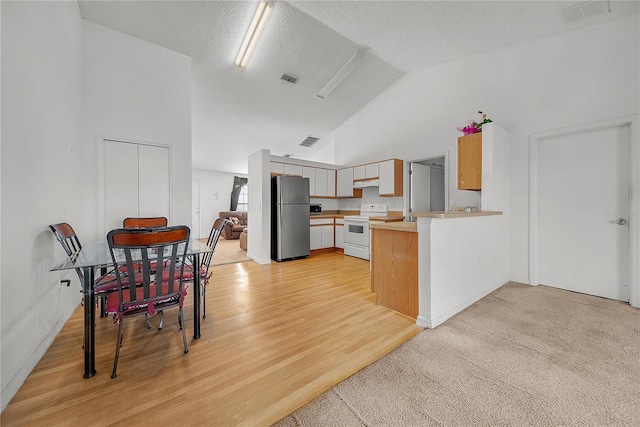 kitchen featuring lofted ceiling, stainless steel fridge, light wood-type flooring, white range with electric stovetop, and kitchen peninsula