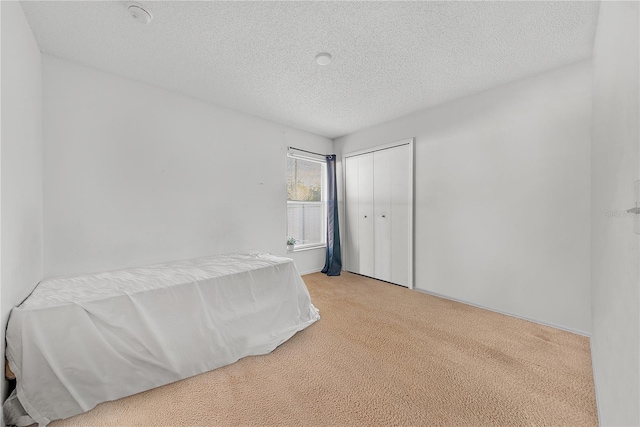 bedroom featuring light carpet, a textured ceiling, and a closet