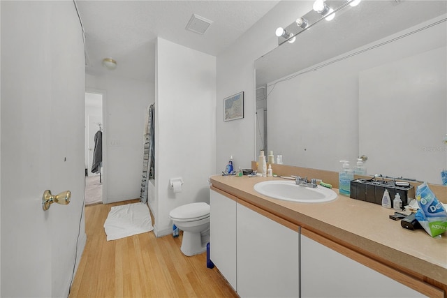 bathroom featuring wood-type flooring, vanity, a textured ceiling, and toilet