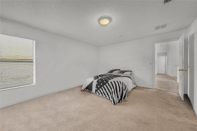 bedroom with a textured ceiling and light carpet