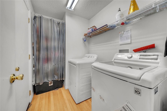 clothes washing area with a textured ceiling, hardwood / wood-style flooring, and washer and clothes dryer