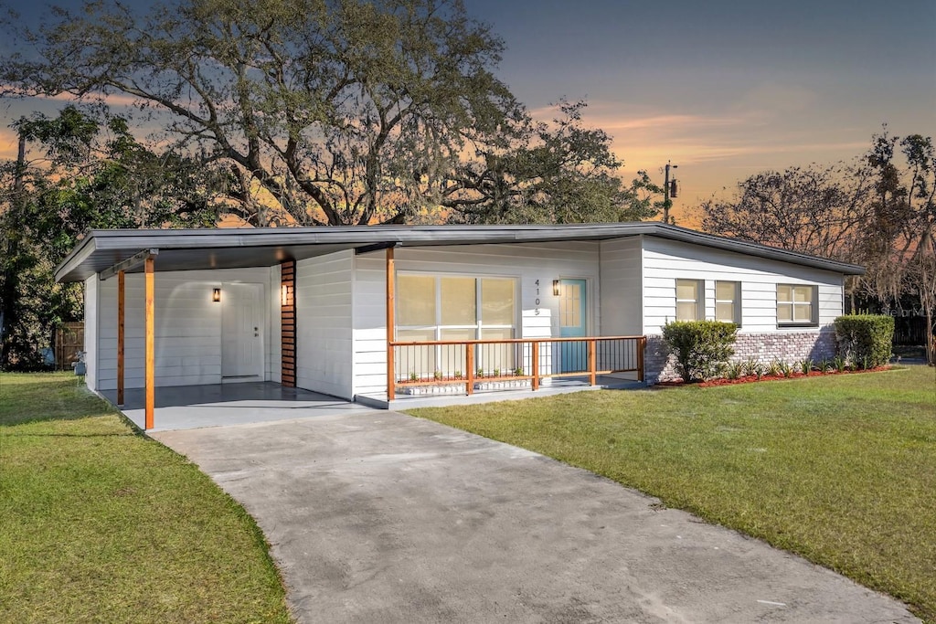 view of front of home with a carport, covered porch, and a yard