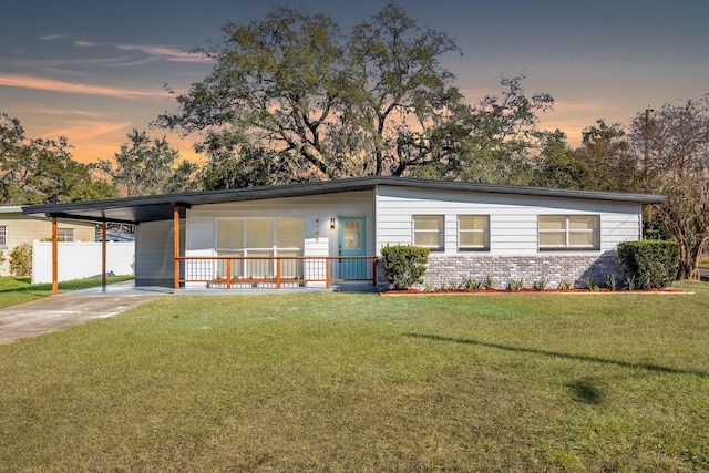 view of front facade featuring a lawn, covered porch, and a carport