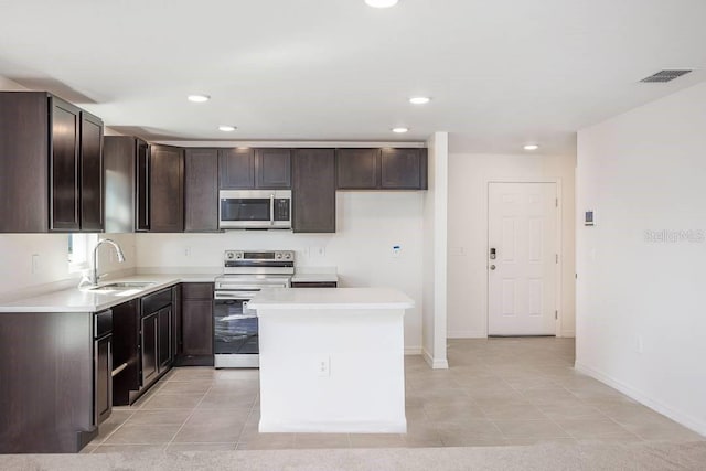 kitchen with sink, a center island, light tile patterned floors, and appliances with stainless steel finishes