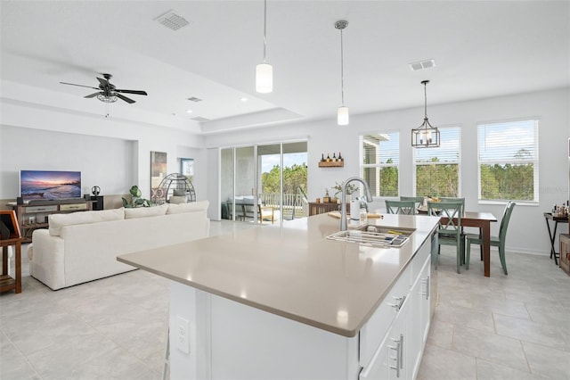 kitchen featuring pendant lighting, a center island with sink, white cabinetry, and sink