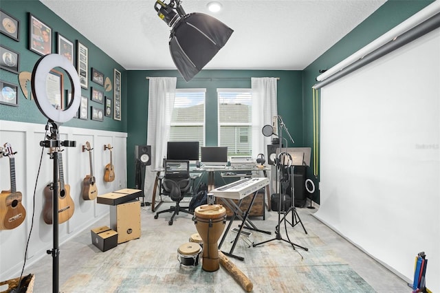 home office featuring a textured ceiling, a wainscoted wall, and concrete floors