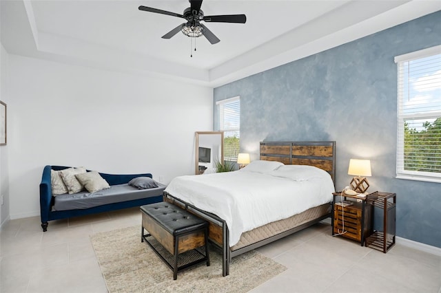 tiled bedroom featuring baseboards, a ceiling fan, and a tray ceiling