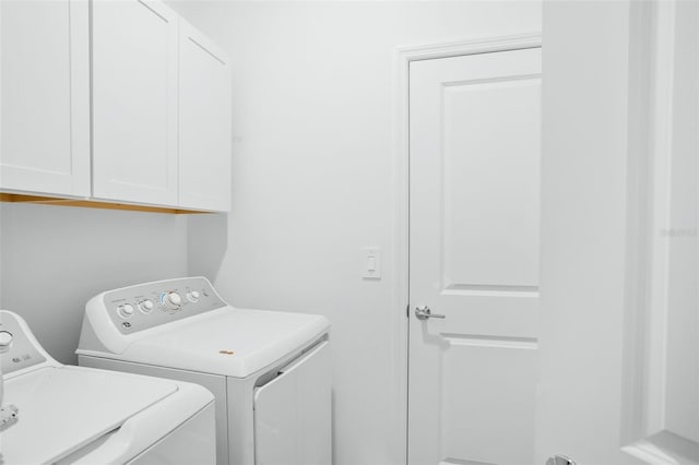 clothes washing area featuring cabinet space and washer and clothes dryer