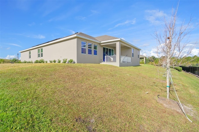 back of property featuring a yard, fence, and stucco siding
