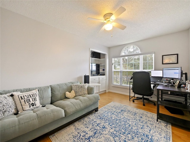 home office featuring light wood-type flooring, a textured ceiling, and ceiling fan