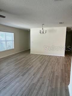 unfurnished room with a chandelier and dark wood-type flooring