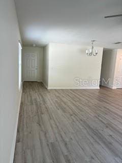 unfurnished room with dark wood-type flooring and a notable chandelier