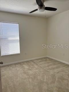 carpeted spare room featuring ceiling fan