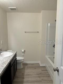 full bathroom featuring vanity, a textured ceiling, toilet, shower / bathing tub combination, and hardwood / wood-style flooring