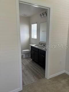 bathroom featuring vanity, wood-type flooring, and toilet