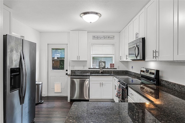 kitchen with dark stone counters, white cabinets, sink, dark hardwood / wood-style floors, and appliances with stainless steel finishes