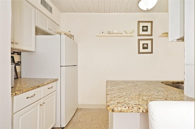 kitchen with white cabinets, white refrigerator, light stone counters, and wooden ceiling