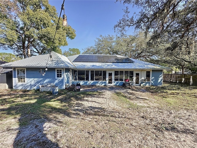 back of property featuring a sunroom and solar panels