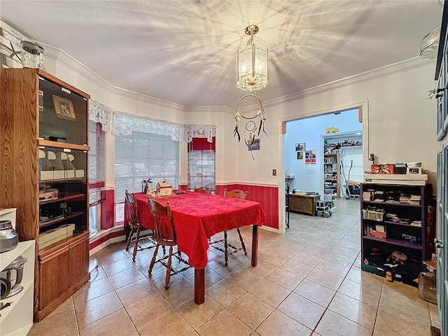 dining room featuring tile patterned flooring, wooden walls, a chandelier, and crown molding