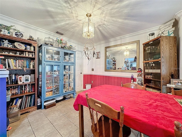 tiled dining room with wood walls, a textured ceiling, and ornamental molding