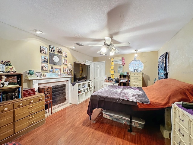 bedroom with a textured ceiling, light hardwood / wood-style flooring, and ceiling fan