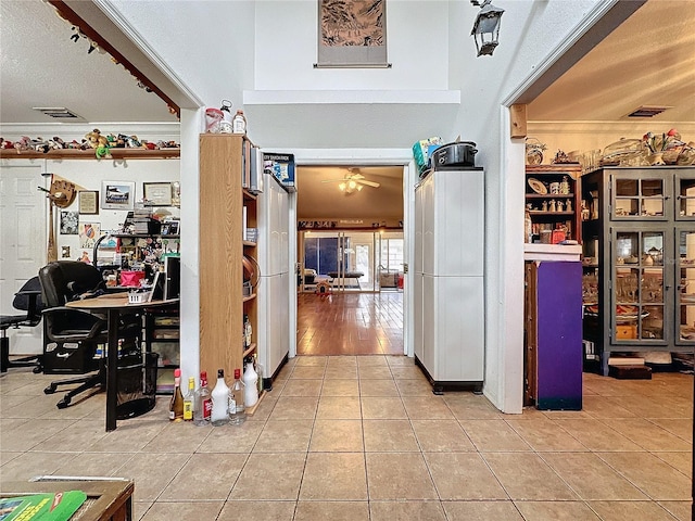 interior space with tile patterned floors, ceiling fan, a textured ceiling, and ornamental molding