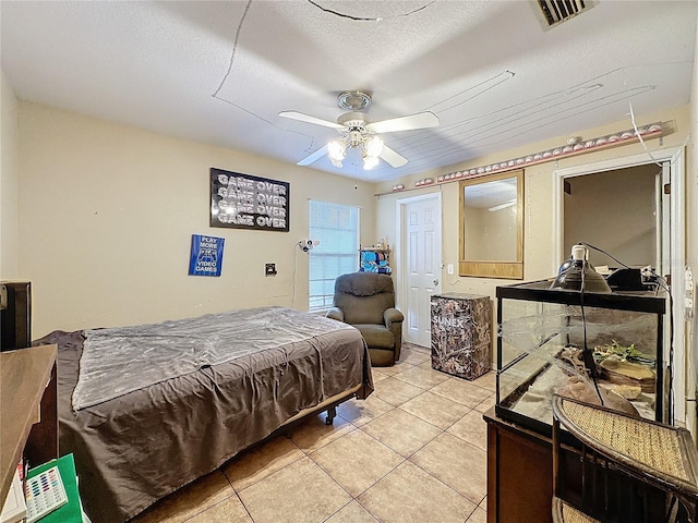 bedroom with ceiling fan, light tile patterned floors, and a textured ceiling