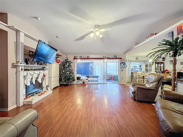 living room with wood-type flooring, a textured ceiling, vaulted ceiling, and ceiling fan