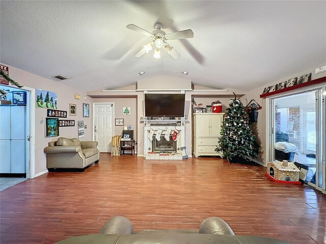 living room with a textured ceiling, ceiling fan, vaulted ceiling, and hardwood / wood-style flooring