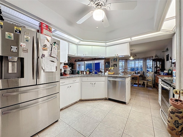 kitchen with white cabinets, ceiling fan, appliances with stainless steel finishes, light tile patterned flooring, and kitchen peninsula