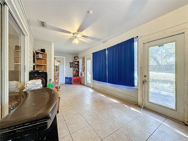 entryway with ceiling fan, light tile patterned floors, and a textured ceiling