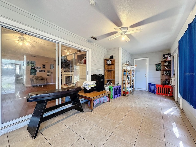 interior space featuring ceiling fan, a textured ceiling, and wooden walls