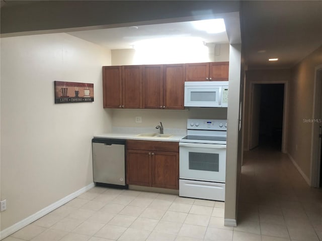 kitchen with white appliances, light tile patterned floors, baseboards, light countertops, and a sink