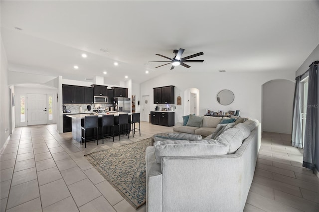 living room with ceiling fan, light tile patterned floors, and vaulted ceiling