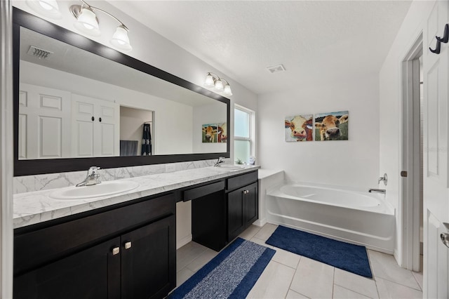 bathroom featuring vanity, a bath, a textured ceiling, and tile patterned flooring