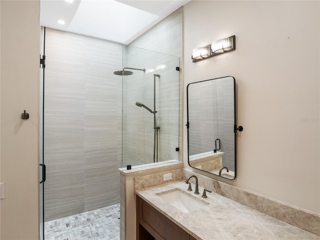 bathroom with a tile shower, vanity, and a skylight