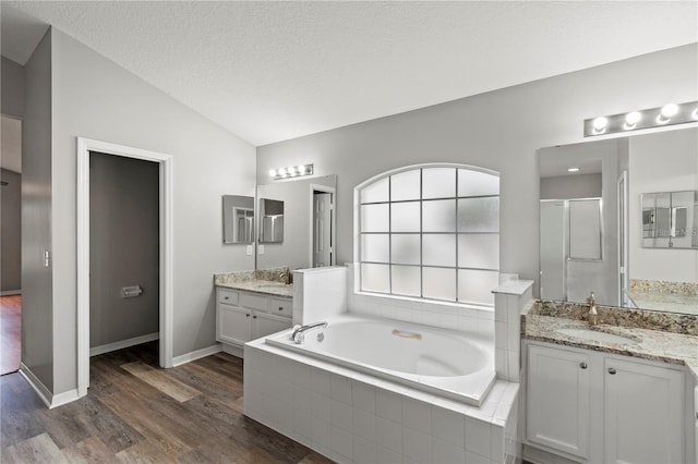 bathroom featuring a textured ceiling, vanity, hardwood / wood-style flooring, shower with separate bathtub, and lofted ceiling