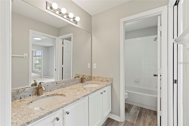 full bathroom with tiled shower / bath combo, wood-type flooring, a textured ceiling, toilet, and vanity