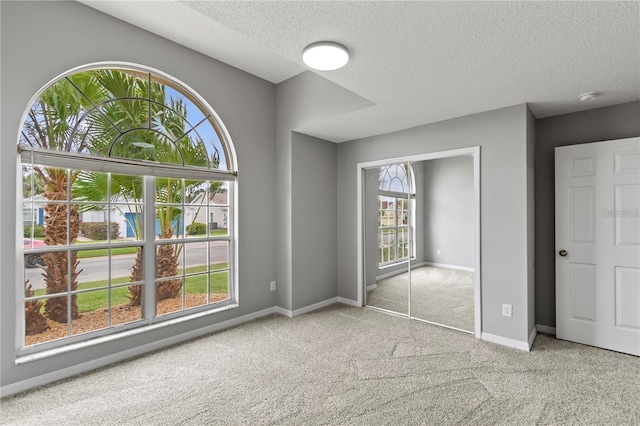 unfurnished bedroom featuring a textured ceiling, light colored carpet, and a closet