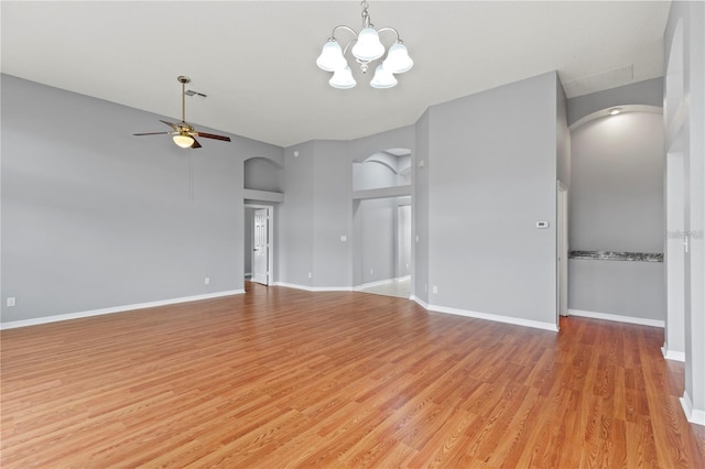 spare room with a towering ceiling, light hardwood / wood-style floors, and ceiling fan with notable chandelier