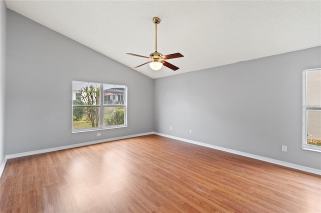 unfurnished room featuring ceiling fan, a healthy amount of sunlight, vaulted ceiling, and light hardwood / wood-style flooring