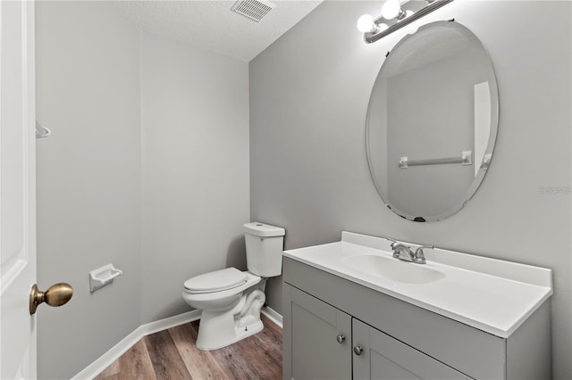 bathroom with vanity, hardwood / wood-style floors, a textured ceiling, and toilet