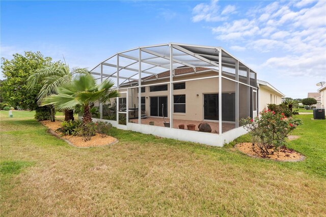 rear view of property with a yard, central AC unit, and a lanai