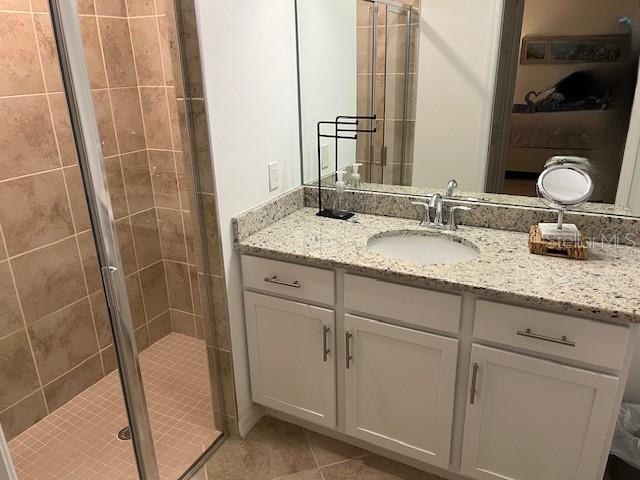 bathroom featuring tile patterned flooring, vanity, and a shower with door