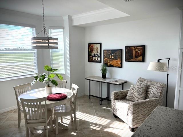 dining space with tile patterned floors, ornamental molding, and an inviting chandelier