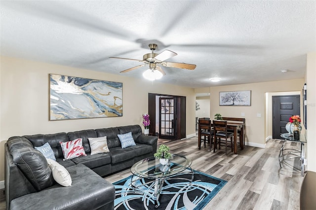 living room featuring wood-type flooring, a textured ceiling, and ceiling fan